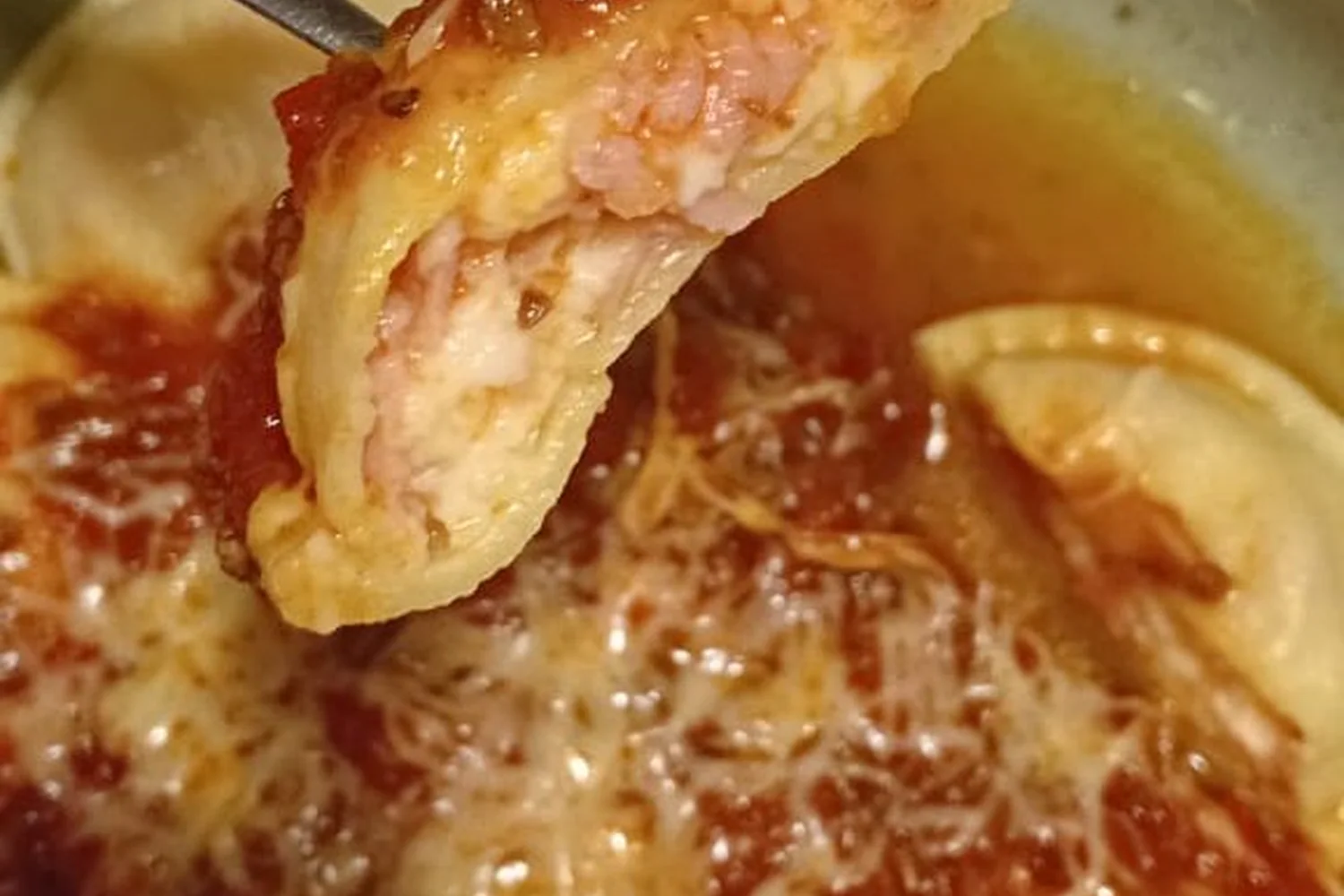 Un bocado de raviolón con salsa levantado con el tenedor