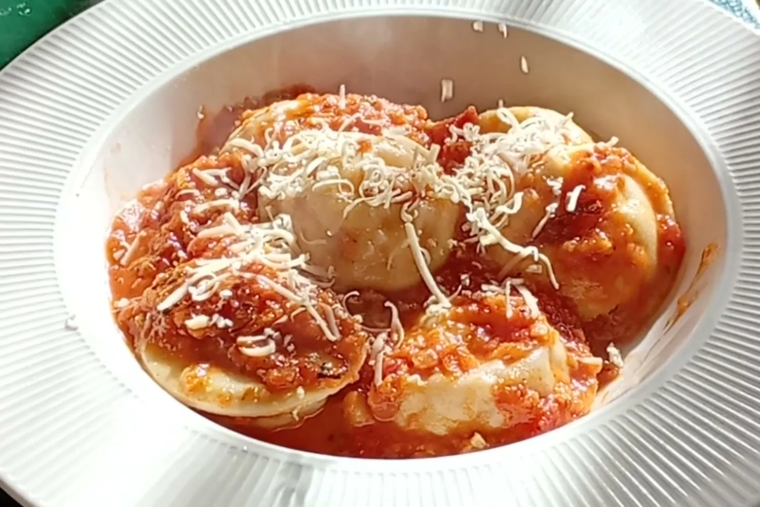 Raviolones calientes con salsa y queso rallado recién puesto