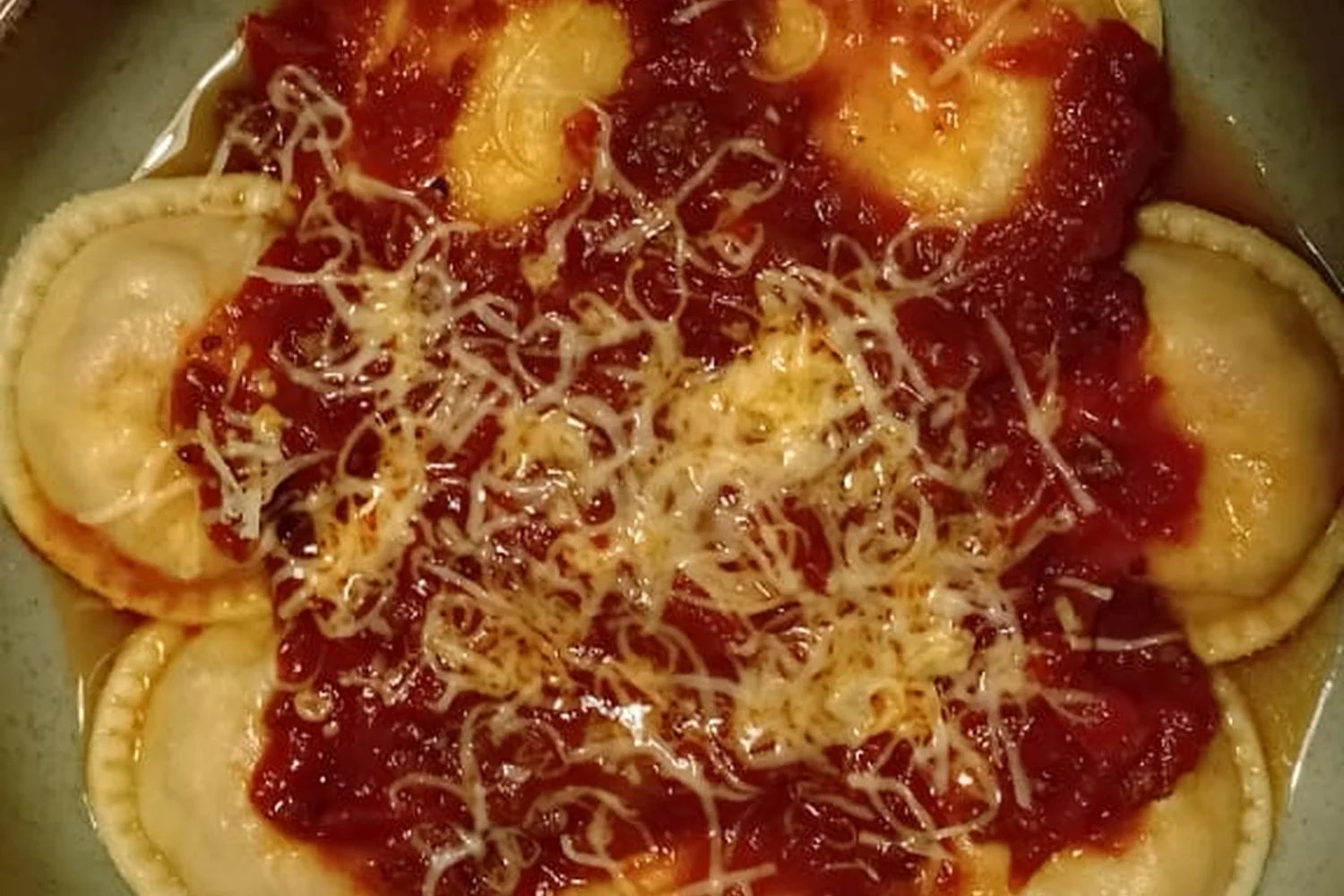 Bowl de raviolones con salsa de tomate y queso rallado